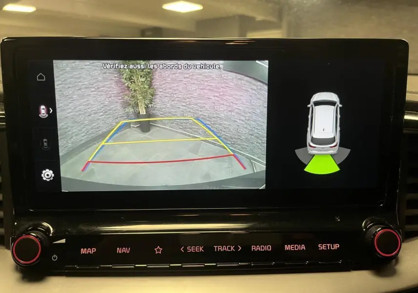Écran tactile intérieur montrant la caméra de recul et l'aide au stationnement du Kia Ceed gris 2023.