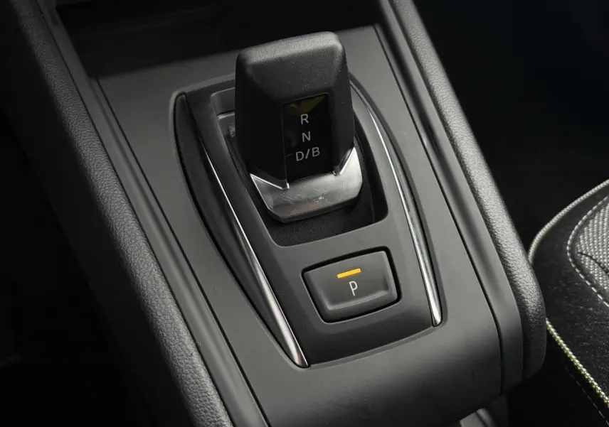 Gros plan sur la commande de boîte automatique et bouton parking du Renault Captur 2025, intérieur noir et coutures contrastées.