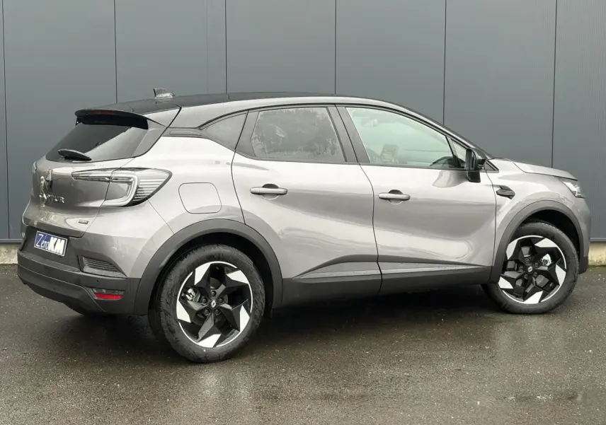 Vue latérale droite d'un Renault Captur 2025 gris Cassiopée avec toit noir étoilé et jantes aluminium 18 pouces.