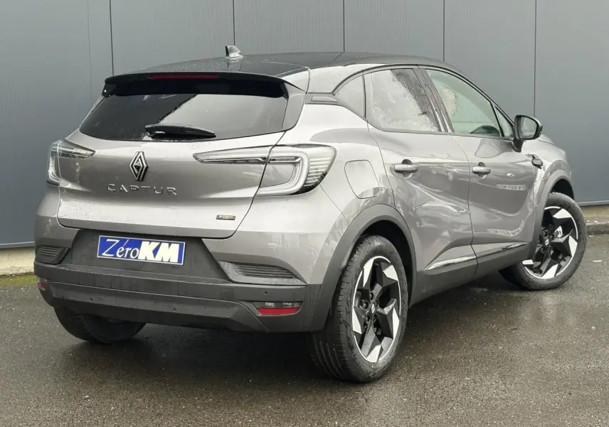 Vue 3/4 arrière droite du Renault Captur gris Cassiopée avec toit noir, jantes 18 pouces et caméra de recul visible.