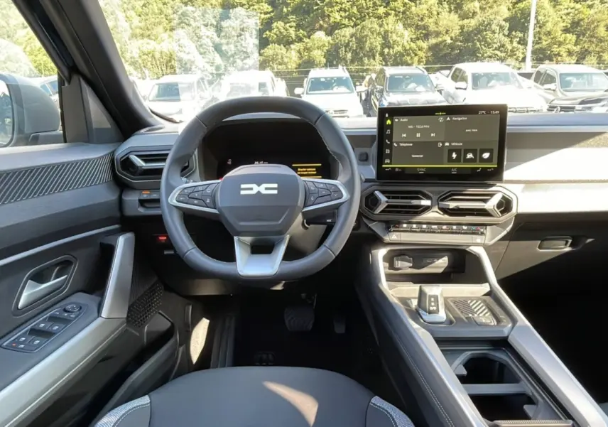 Vue intérieure frontale du tableau de bord du Dacia Bigster Hybrid 155, avec volant cuir et écran tactile 10,1 pouces.