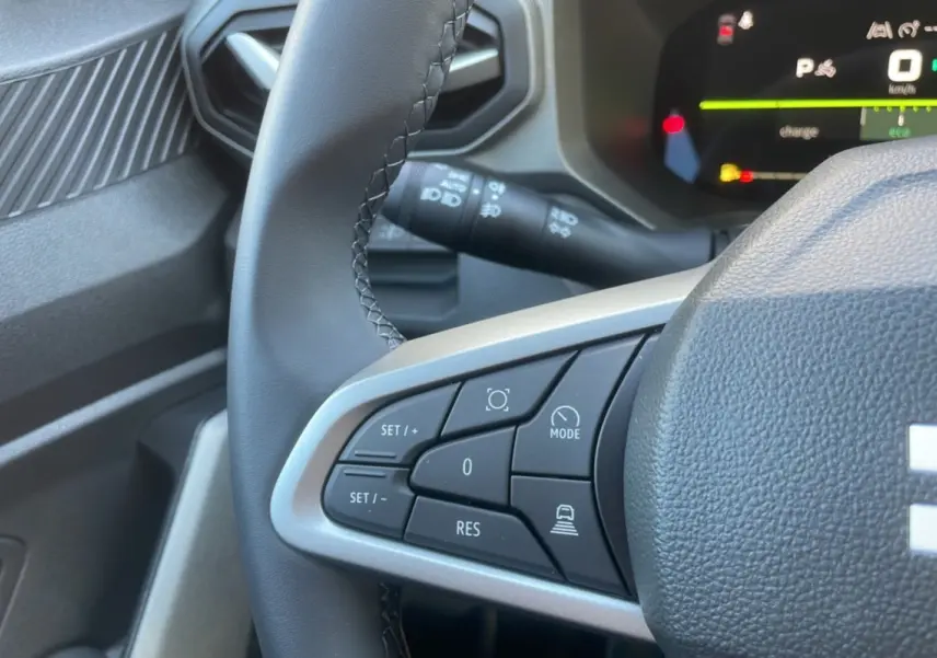 Gros plan sur le volant cuir noir du Dacia Bigster 2025, montrant les commandes de régulateur et tableau de bord digital.