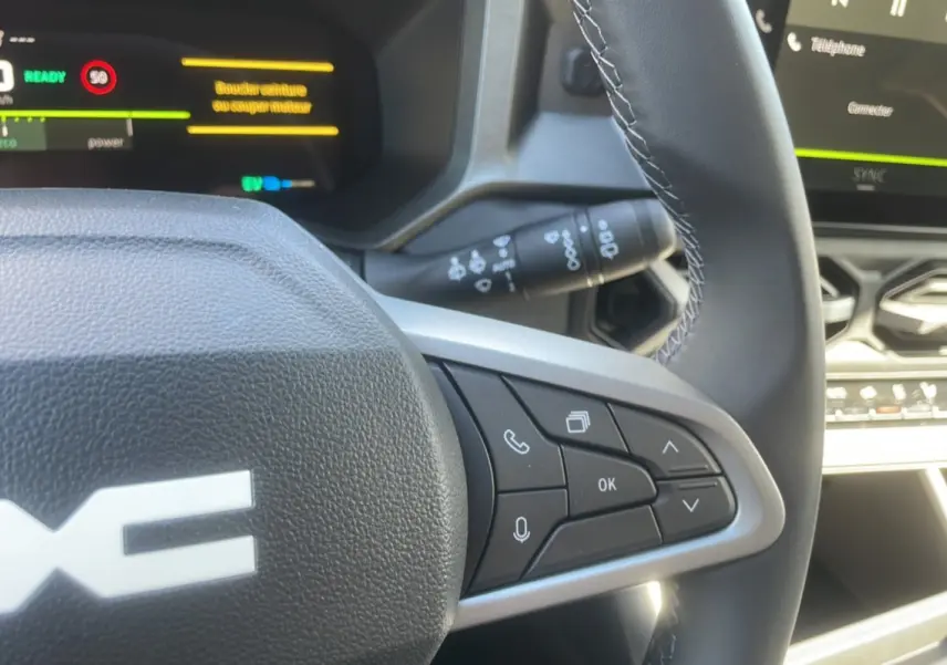 Gros plan sur le volant cuir de la Dacia Bigster Hybrid 155, avec commandes multifonctions et tableau de bord digital.