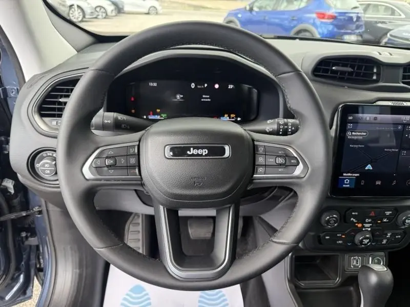 Vue intérieure centrée sur le volant du Jeep Renegade 2024, avec tableau de bord numérique et écran tactile visible.