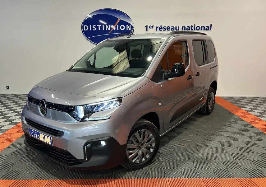 Citroën Berlingo Multispace gris acier en 3/4 avant droit, avec barres de toit noir brillant et phares LED allumés.