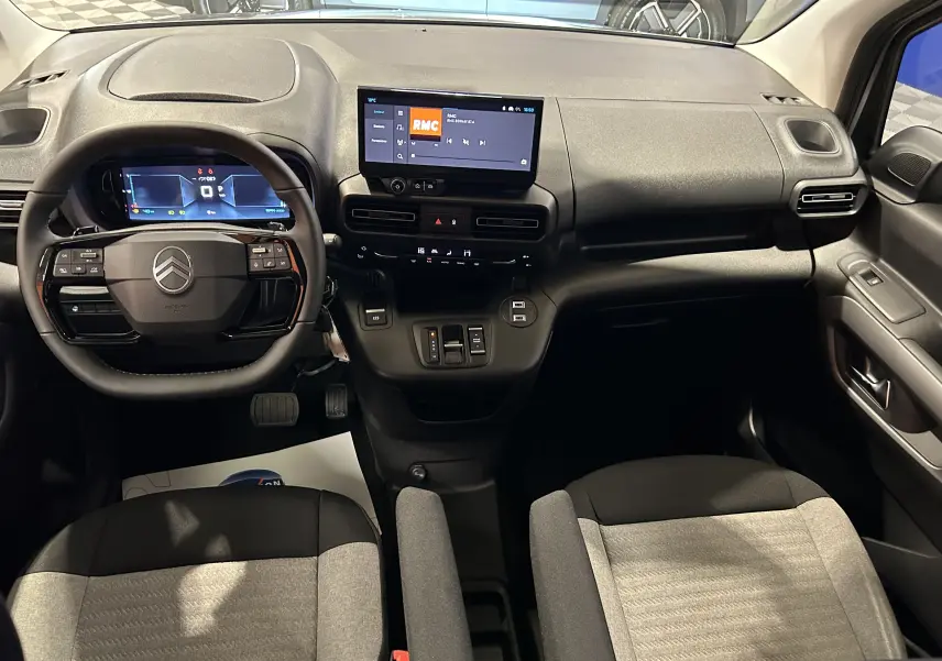 Vue intérieure avant du Citroën Berlingo Multispace 2026, tableau de bord noir avec écran tactile et sièges tissu gris.