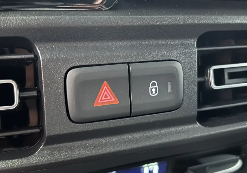 Gros plan sur les boutons d'alerte et de verrouillage centralisé du tableau de bord du Citroën Berlingo Multispace gris acier.