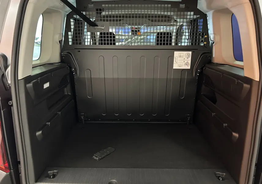 Vue intérieure du coffre du Citroën Berlingo Multispace gris acier, avec cloison métallique de séparation et espace de chargement vide.