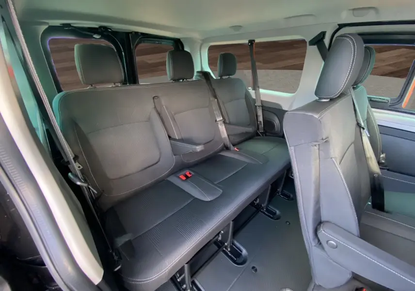 Vue intérieure du Renault Trafic Combi noir montrant les sièges arrière en tissu noir avec ceintures et appuie-têtes.