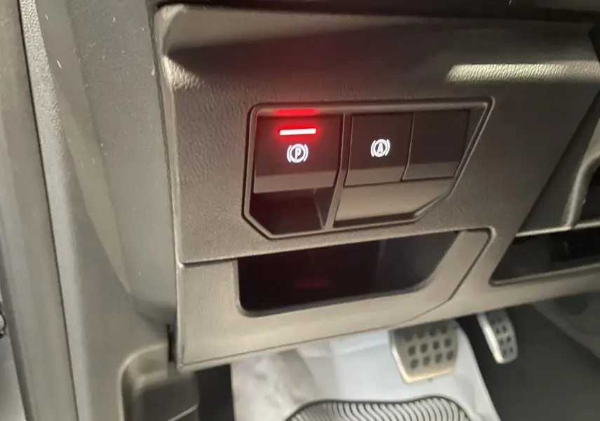 Gros plan sur les commandes électroniques du frein à main et du système start-stop dans un Renault Austral 2025 gris schiste.