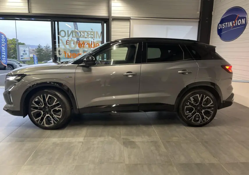 Renault Austral 2025 gris schiste avec toit noir étoilé, vue profil côté gauche en intérieur showroom.