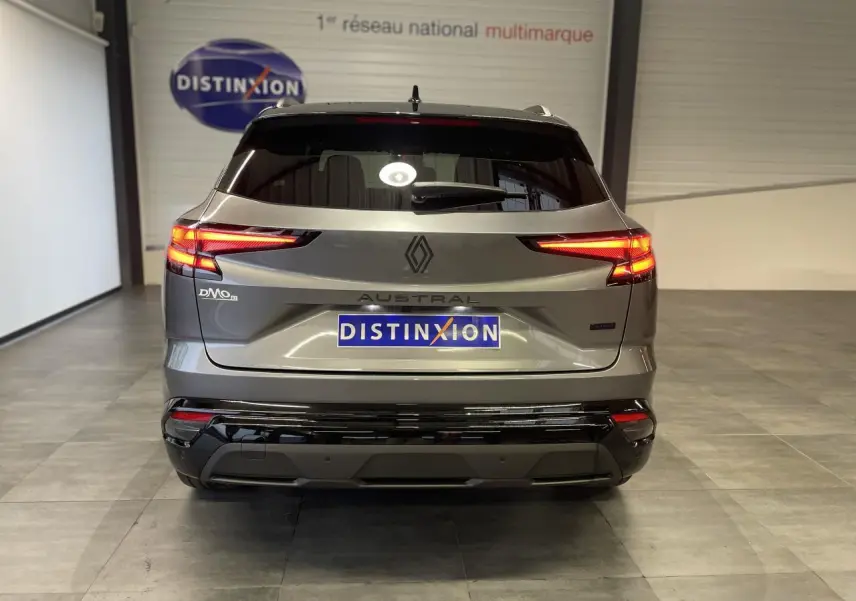 Vue arrière du Renault Austral 2025 gris Schiste métallisé avec toit noir étoilé, feux arrière allumés en intérieur showroom.