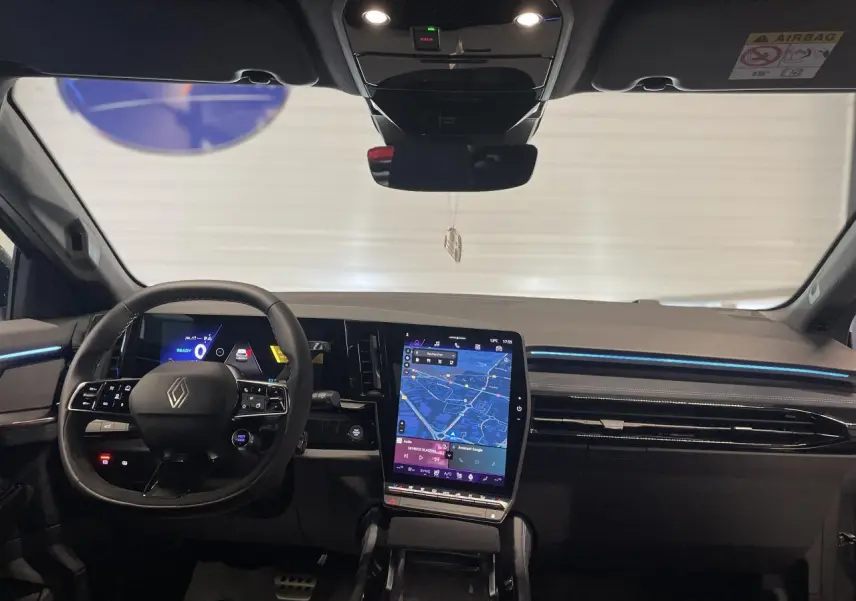 Vue intérieure du tableau de bord du Renault Austral 2025 avec écran tactile vertical et éclairage d'ambiance bleu.