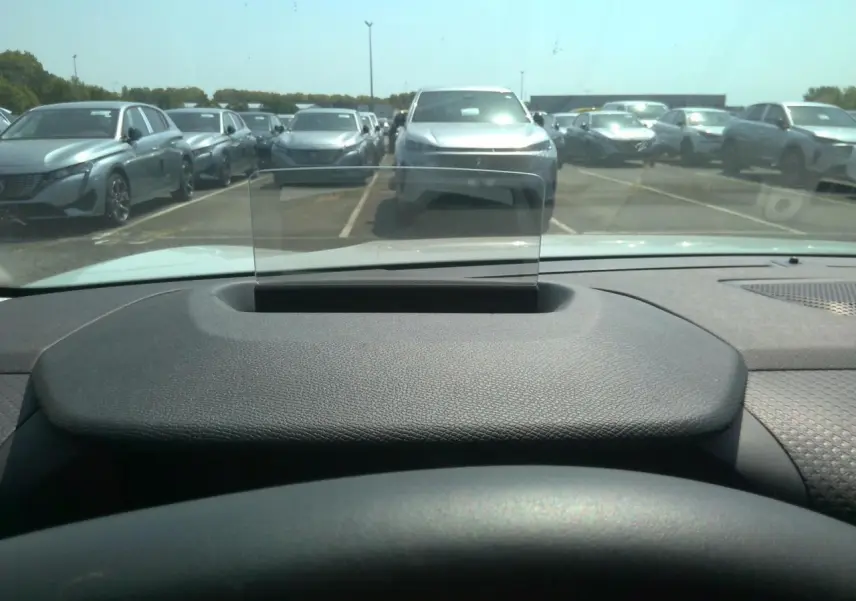 Vue depuis l'intérieur d'une Citroën C4 Hybrid blanche, avec affichage tête haute et tableau de bord noir texturé.