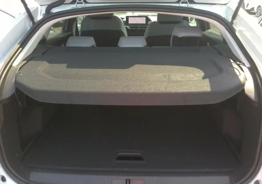 Coffre ouvert vu de l'arrière d'une Citroën C4 Hybrid 145 blanc Okénite avec tablette cache-bagages et sièges arrière visibles.