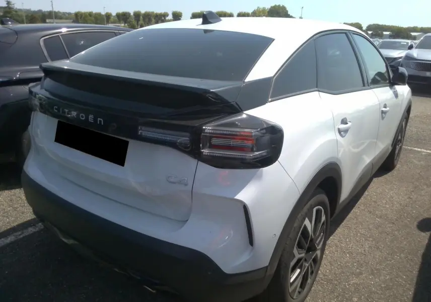 Vue 3/4 arrière droite d'une Citroën C4 blanche Okénite avec toit noir et feux arrière fumés.