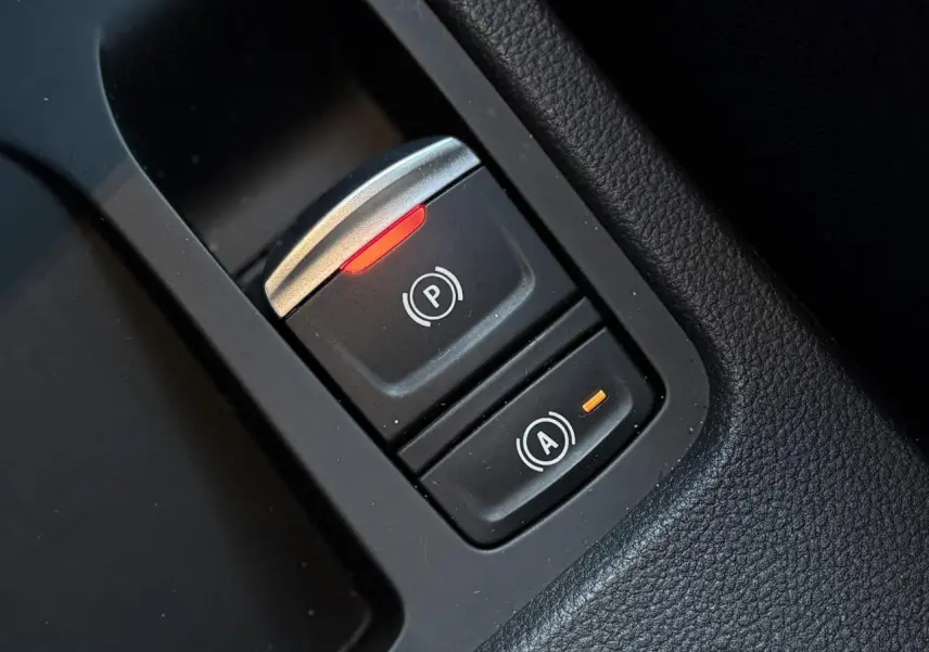 Gros plan sur les boutons du frein de parking électronique et de l'arrêt automatique dans l'habitacle noir de la Renault Clio Gris Schiste.