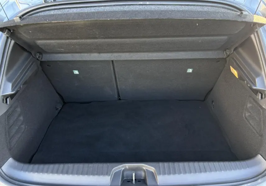 Coffre ouvert vu de face de la Renault Clio V E-Tech Full Hybrid 145 Techno gris Schiste, intérieur noir.