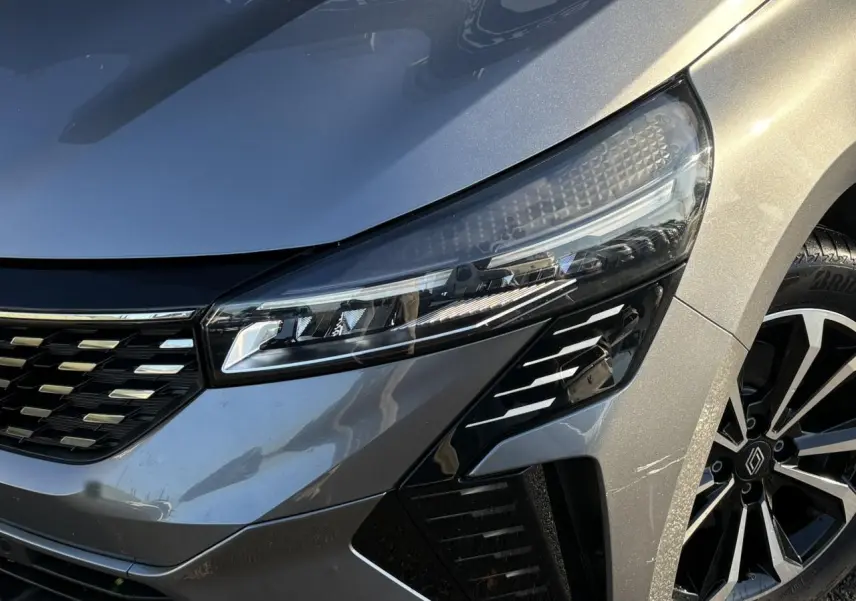 Gros plan sur l'avant droit de la Renault Clio V E-Tech Gris Schiste, mettant en valeur son phare LED et jante alliage noire.