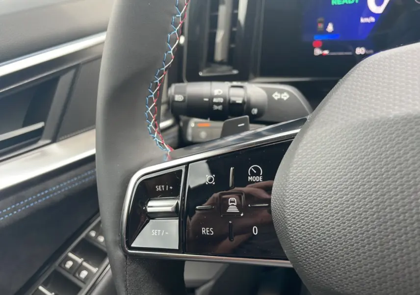 Gros plan sur le volant cuir multifonctions avec surpiqûres tricolores du Renault Austral gris schiste, version Esprit Alpine.