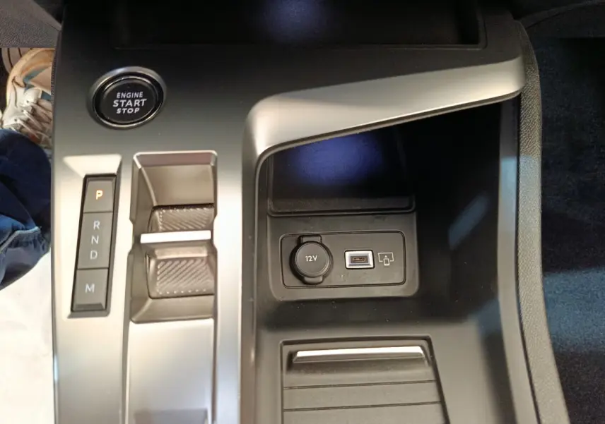 Gros plan sur la console centrale de la Peugeot 308 blanche, avec bouton start, levier de boîte auto et prise 12V/USB.