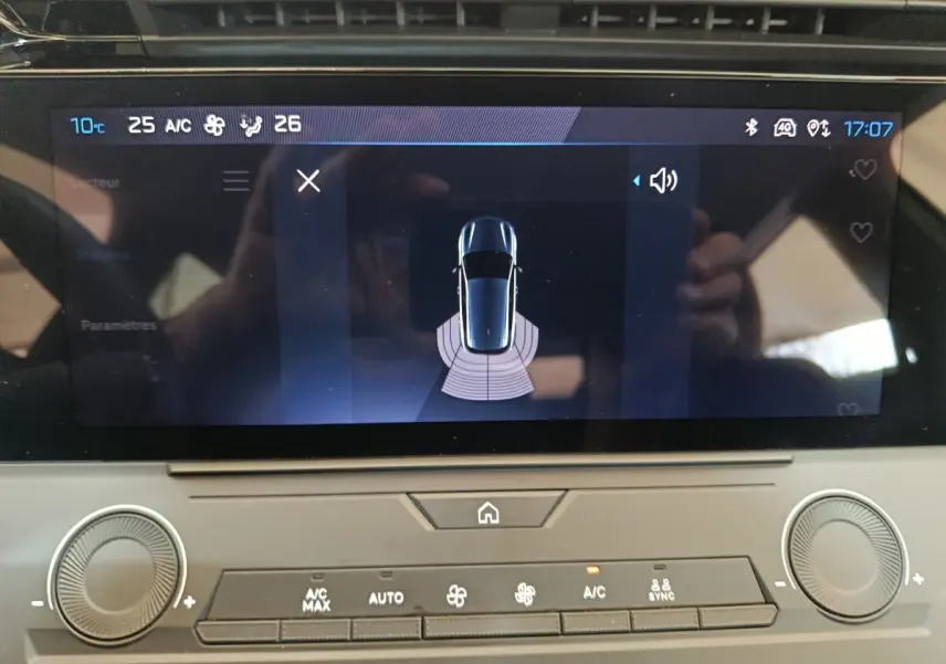 Écran tactile central de la Peugeot 308 blanc, affichant l'aide au stationnement vue de dessus.