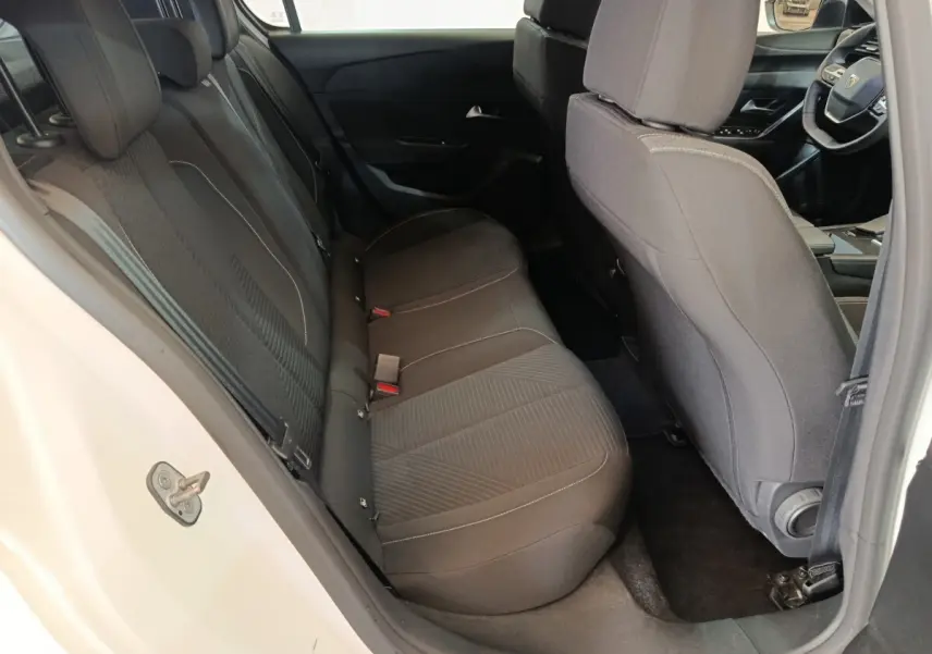 Vue intérieure côté gauche sur les sièges arrière noirs d'une Peugeot 308 blanche avec tableau de bord partiellement visible.