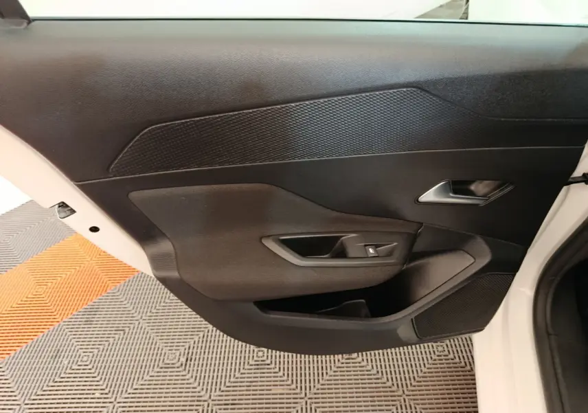 Vue intérieure de la porte côté droit de la Peugeot 308 blanche, avec poignée argentée et commande de lève-vitre noir.