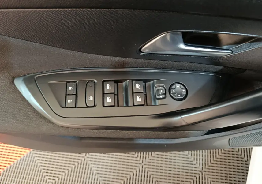 Vue rapprochée des commandes de lève-vitres et rétroviseurs côté conducteur d'une Peugeot 308 blanche de 2022.