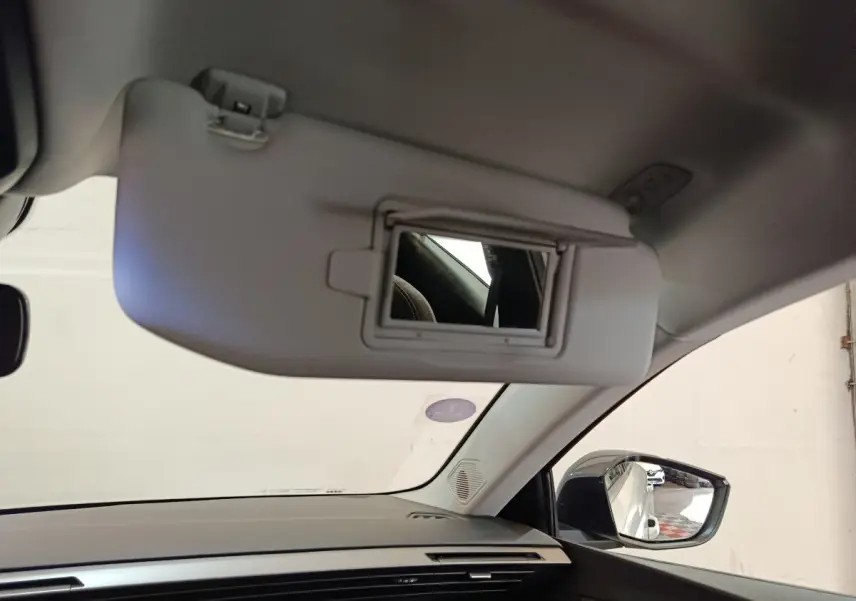 Détail intérieur du pare-soleil avec miroir ouvert côté conducteur d'une Peugeot 308 blanche, vue du siège avant.