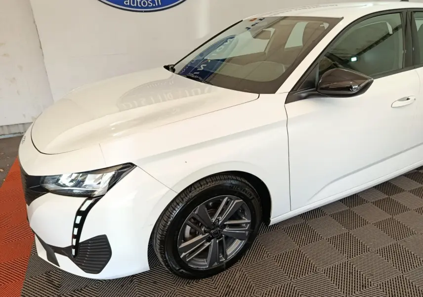 Vue 3/4 avant droit d'une Peugeot 308 blanche avec phares LED et jantes alliage foncé.