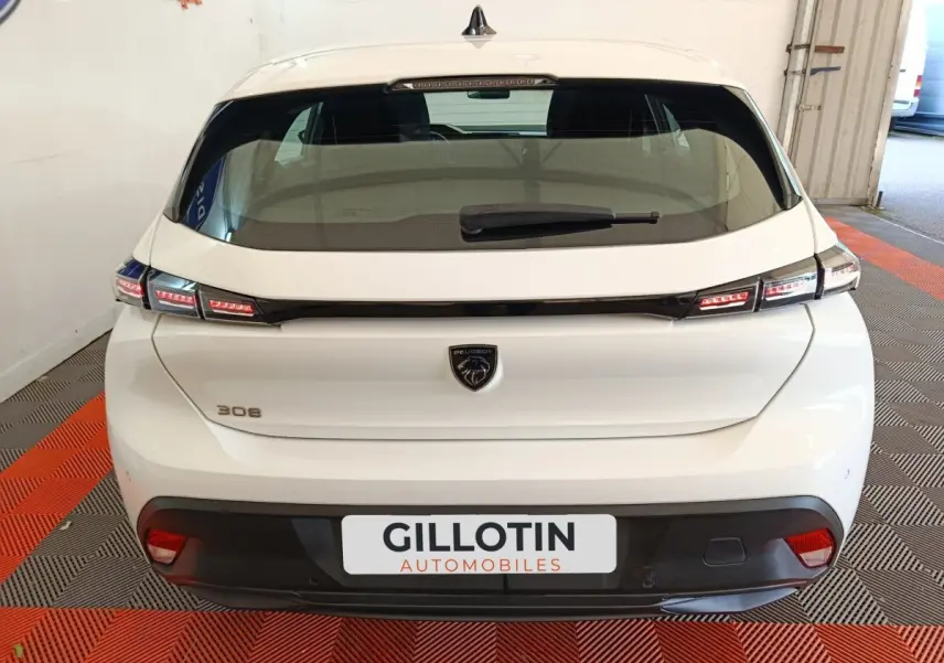 Vue arrière d'une Peugeot 308 blanche de 2022 avec feux LED et logo lion distinctif au centre du hayon.