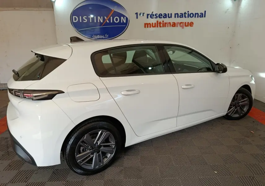 Peugeot 308 blanche vue de profil côté droit, avec jantes alliage et feux arrière LED distinctifs.