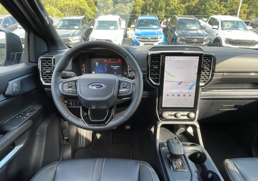 Vue intérieure frontale du Ford Ranger 2025 avec volant cuir, écran tactile vertical et sellerie noire.