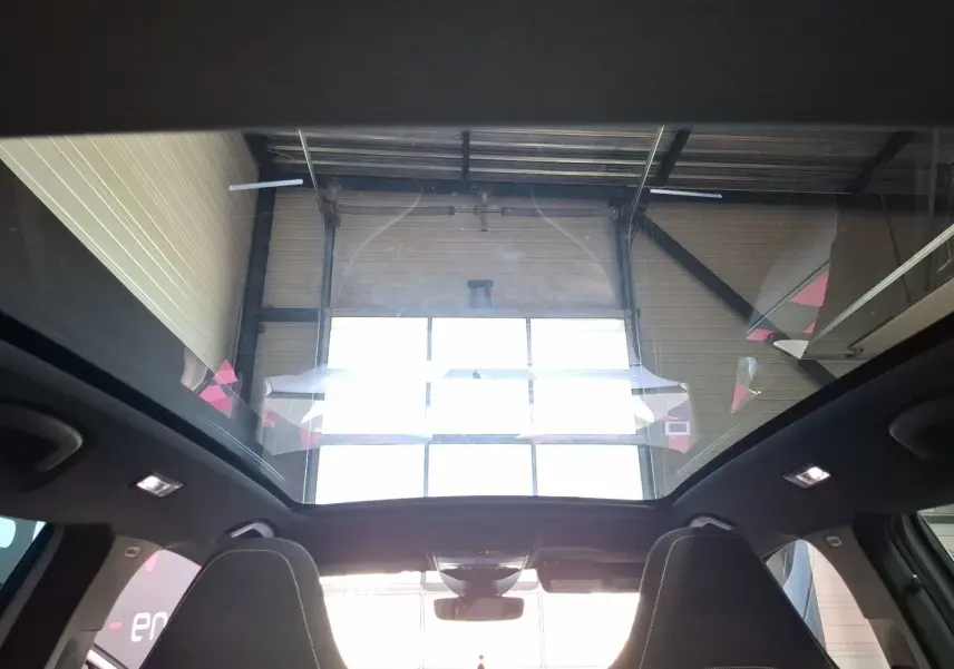 Vue intérieure du toit panoramique du Skoda Kamiq blanc 2021, mettant en valeur l'espace lumineux au-dessus des sièges avant.