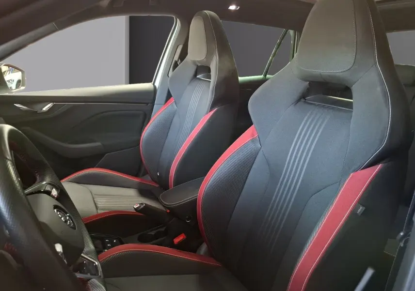 Vue intérieure côté gauche montrant les sièges baquets noirs avec surpiqûres rouges et toit panoramique du Skoda Kamiq blanc.