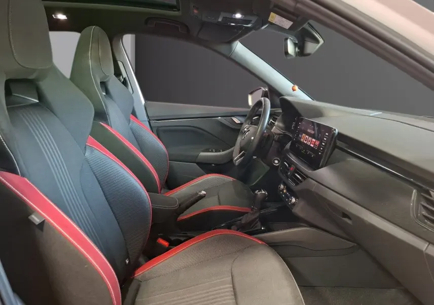 Vue intérieure côté conducteur du Skoda Kamiq 2021, sièges sport noirs avec surpiqûres rouges et tableau de bord moderne.