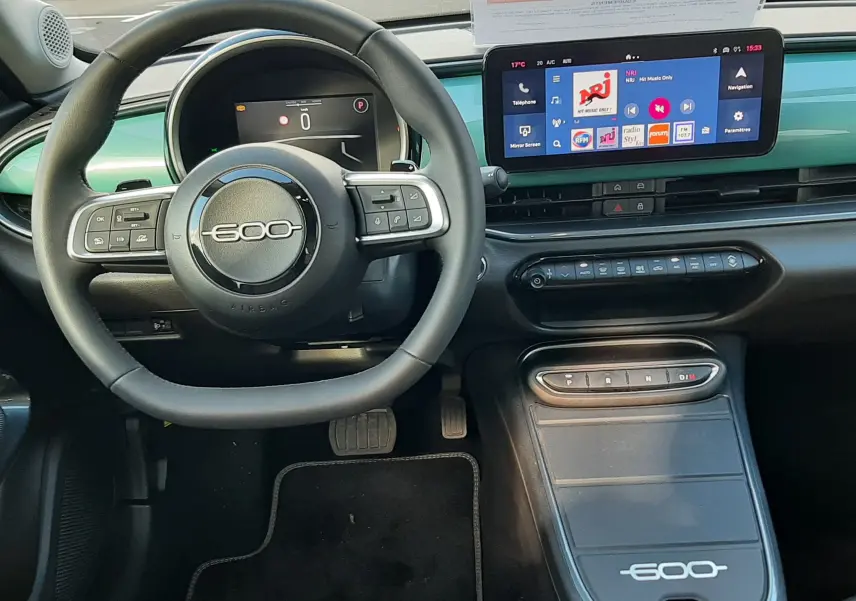 Vue intérieure avant de la FIAT 600 1.2 Hybrid 2025, tableau de bord vert Sky avec volant et écran tactile moderne.