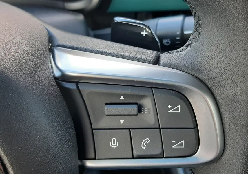 Gros plan sur les commandes au volant côté droit du Fiat 600 1.2 Hybrid 2025, intérieur noir et gris.