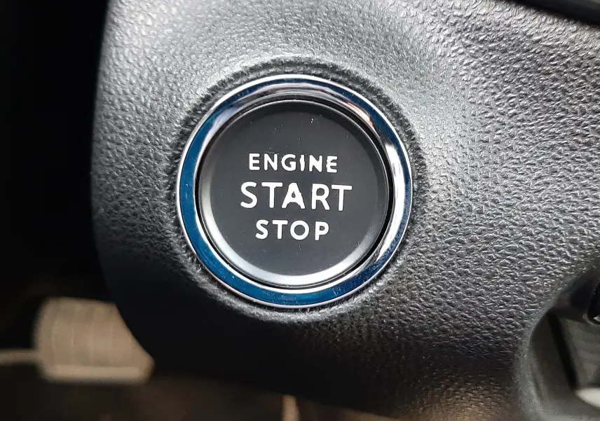 Bouton rond de démarrage moteur "Engine Start Stop" sur tableau de bord noir texturé d'une Fiat 600 hybride 2025.