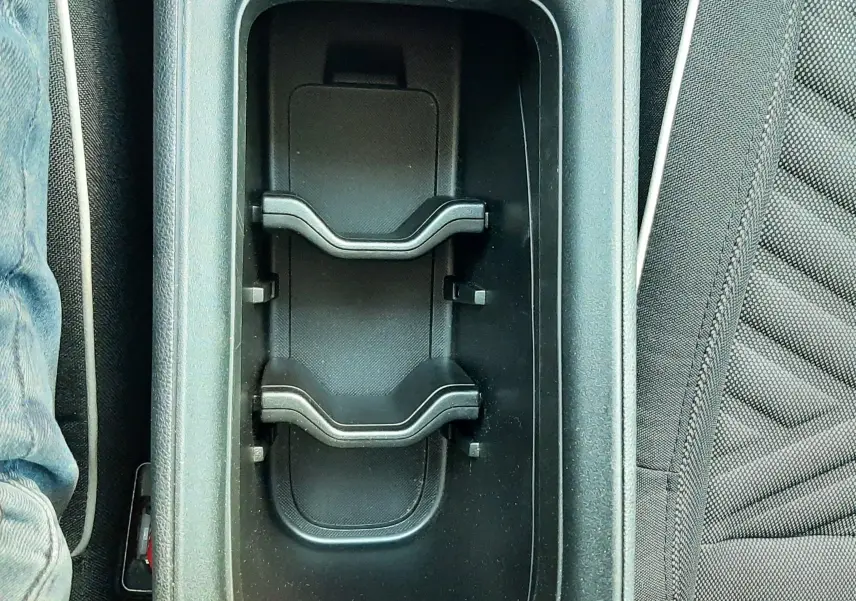 Gros plan sur le porte-gobelets central noir entre les sièges avant gris foncé d'une FIAT 600 2025.