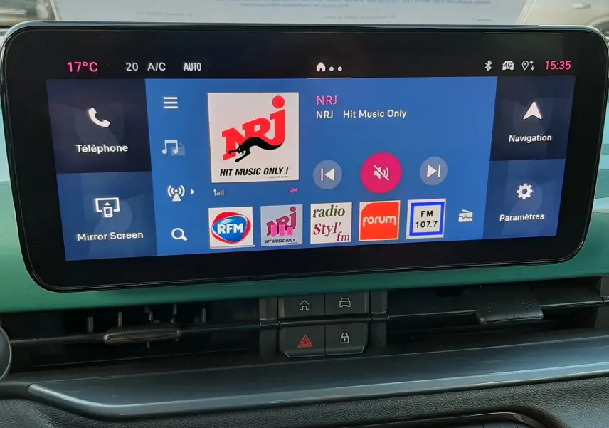 Vue intérieure du tableau de bord du FIAT 600 vert Sky 2025, avec écran tactile multimédia affichant radio NRJ.