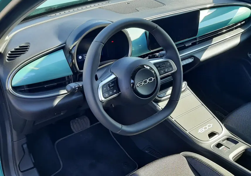 Vue de profil côté gauche d'une FIAT 600 1.2 Hybrid 2025 en vert Sky avec jantes noires à motifs blancs.