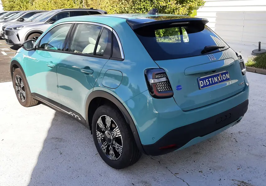 Vue 3/4 arrière droite d'une FIAT 600 1.2 Hybrid 2025 en vert Sky avec toit noir et jantes stylisées.
