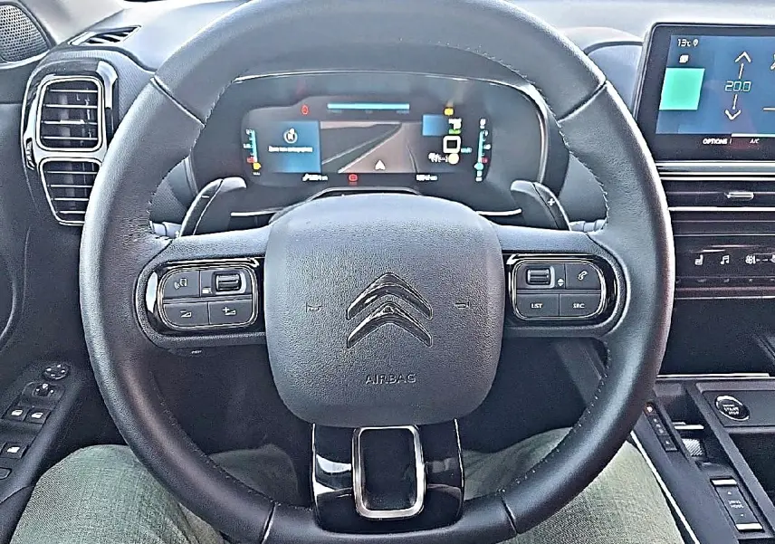 Vue frontale du volant cuir noir et du tableau de bord numérique du Citroën C5 Aircross hybride 2024.