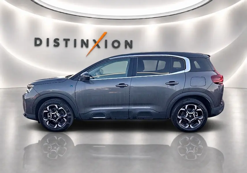 Profil côté gauche du Citroën C5 Aircross gris platinium 2024 avec jantes alu et barres de toit visibles.