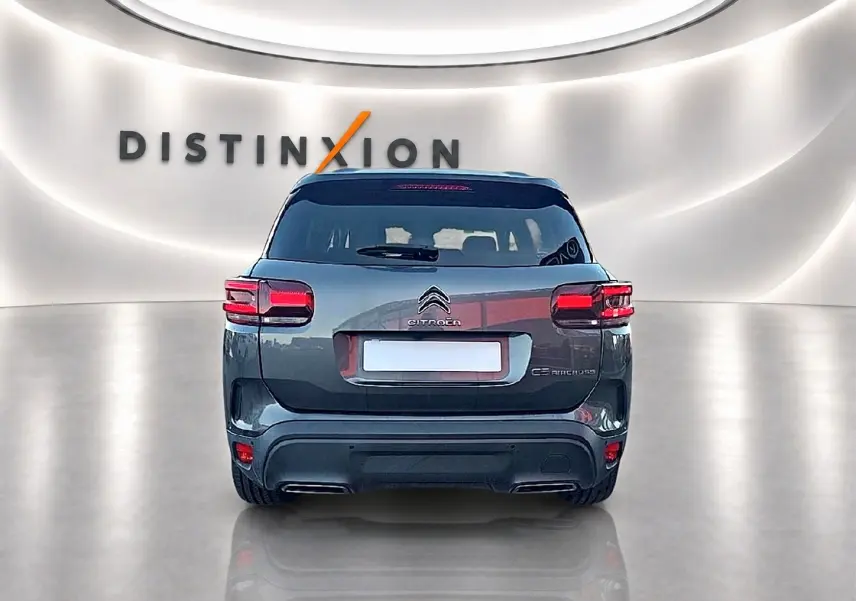 Vue arrière du Citroën C5 Aircross gris platinium 2024 dans un showroom avec éclairage moderne et logo Distinxion.