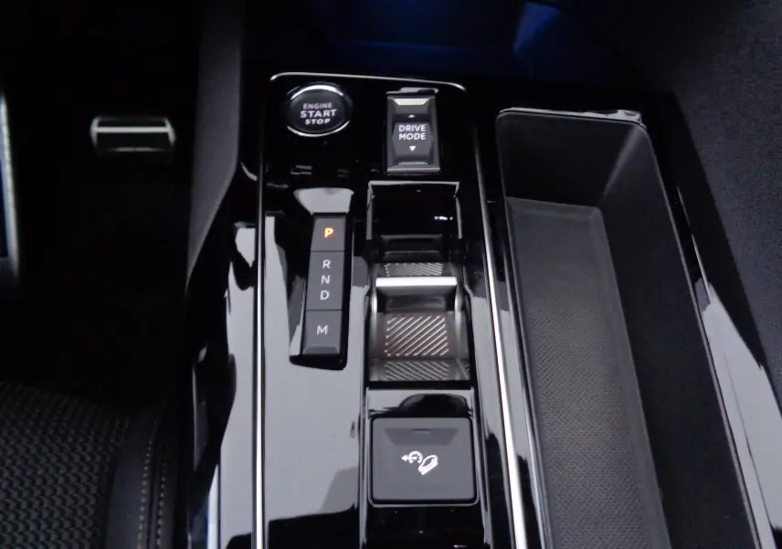 Gros plan sur la console centrale noire brillante du Peugeot 3008 2023, avec levier de vitesses automatique et bouton start-stop.