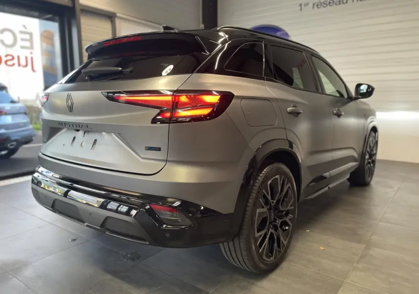 Vue 3/4 arrière droite du Renault Austral gris satin mat avec toit noir et jantes alliage noires en showroom.