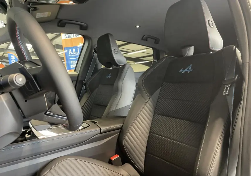 Vue intérieure côté conducteur du Renault Austral Esprit Alpine 2025, sièges en cuir noir avec logo Alpine bleu brodé.